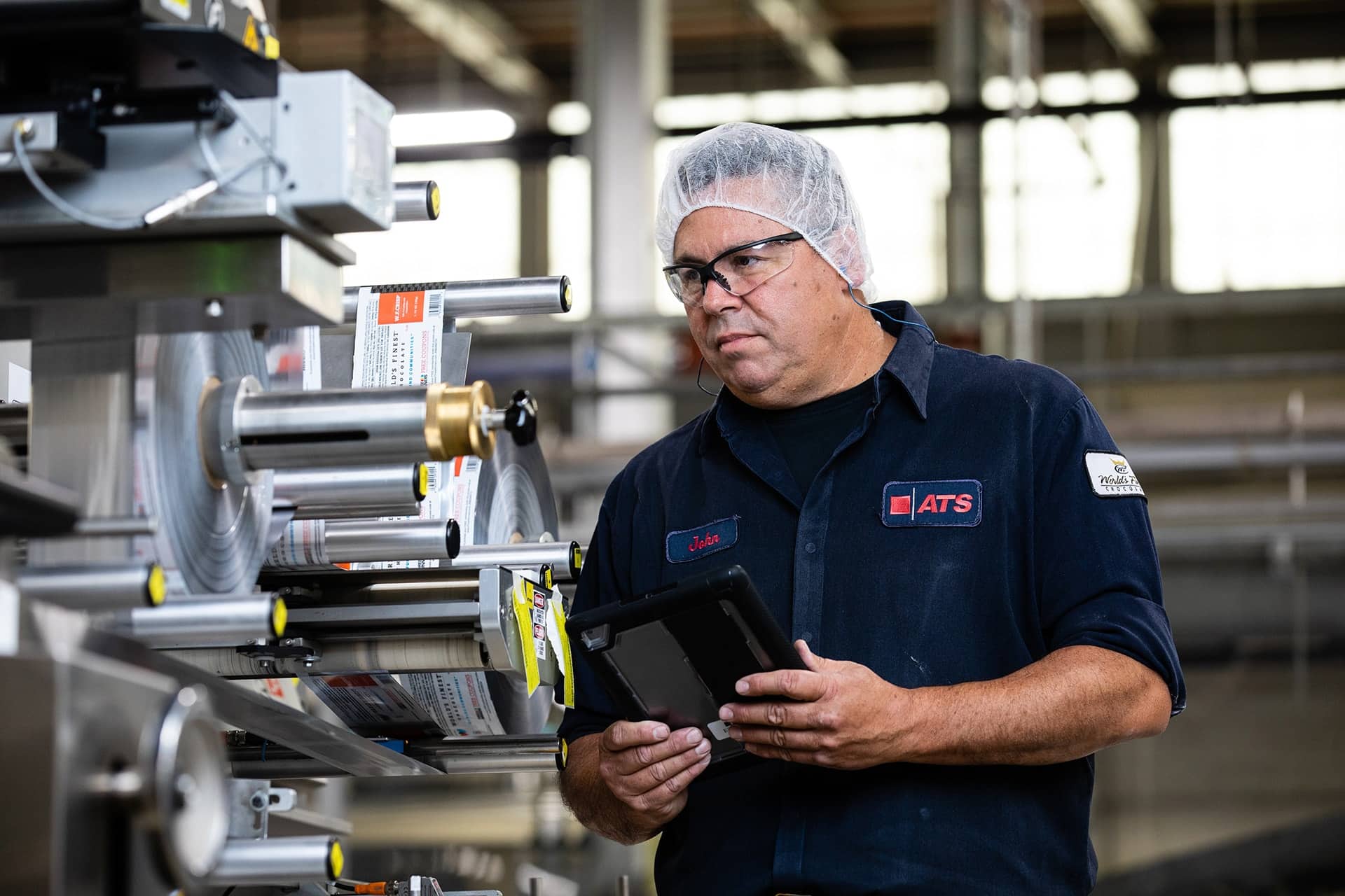 Man in a hard hat carrying a tablet in a factory