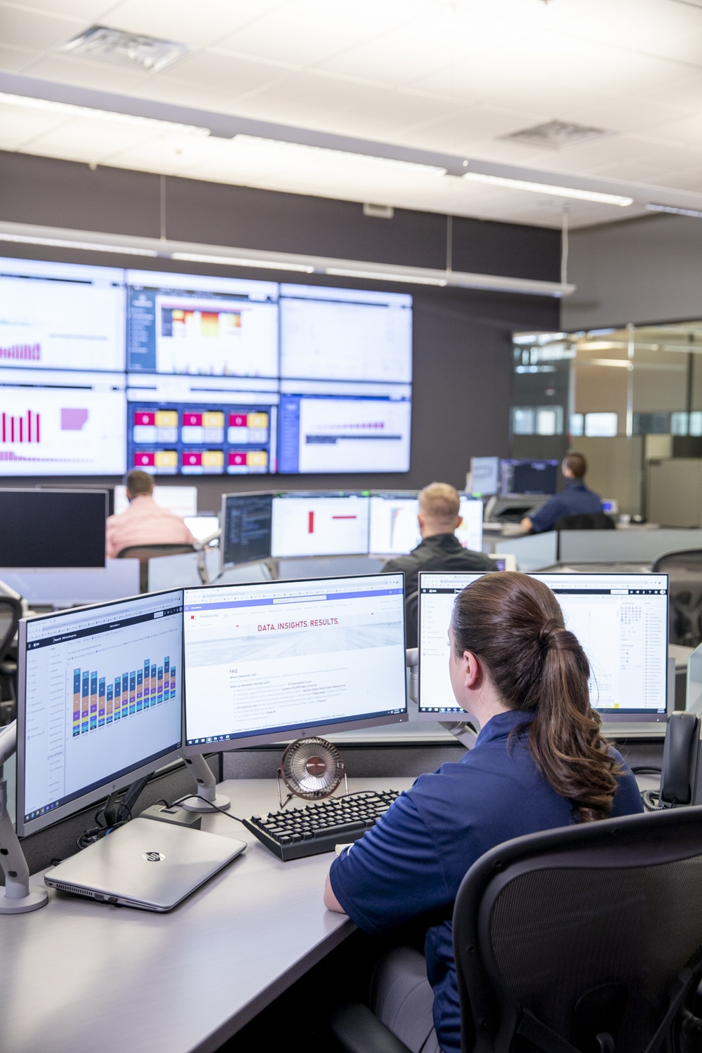 Four people in room assessing data on monitors.