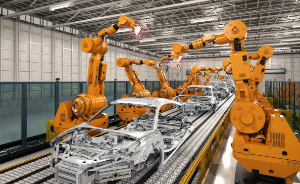 Large yellow robotic claws building car frames in factory