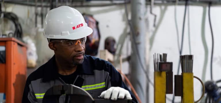 Man wearing hard hat, glasses and gloves in factory