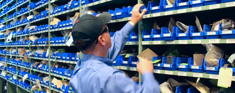 Man in cap retrieving something from shelved container