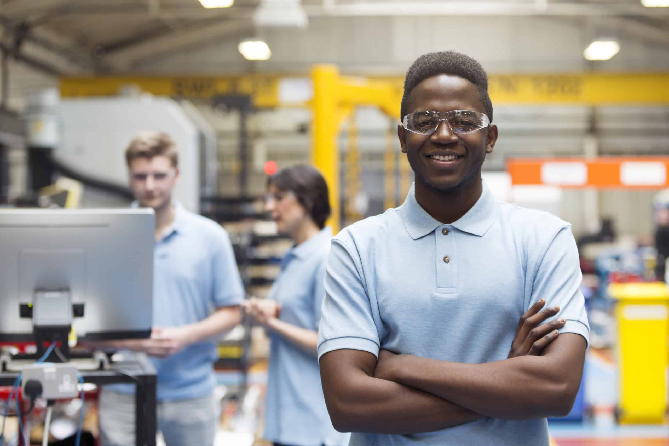 Apprentice standing proud in factory setting.
