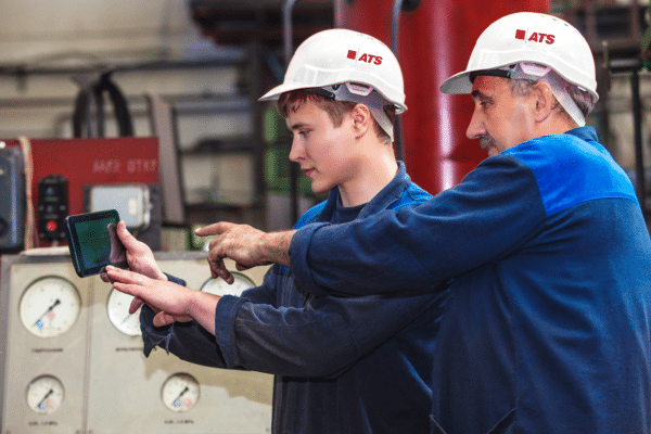 Two men working at a factory with hard hats