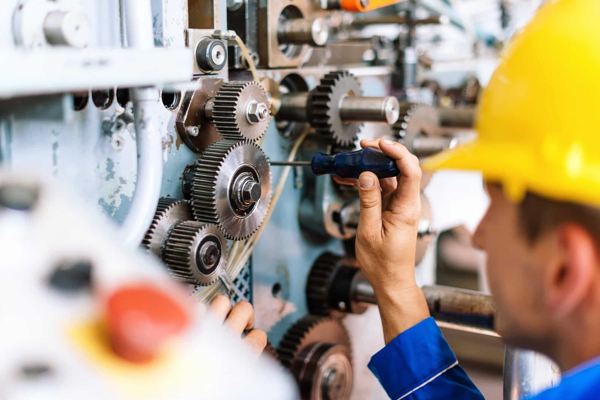 Technician in hard hat fixing gears.