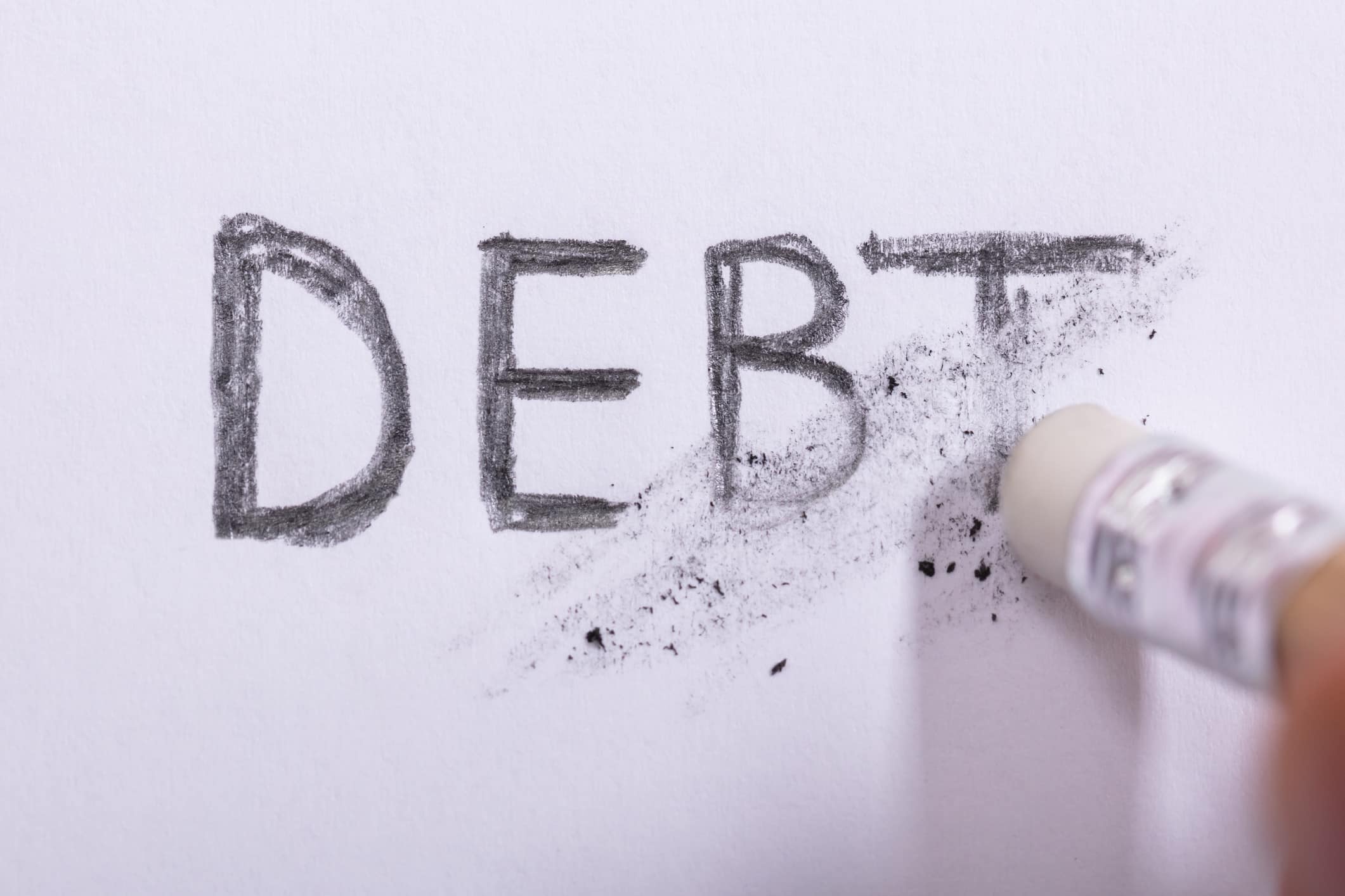 Pencil erasing "debt" on white paper.