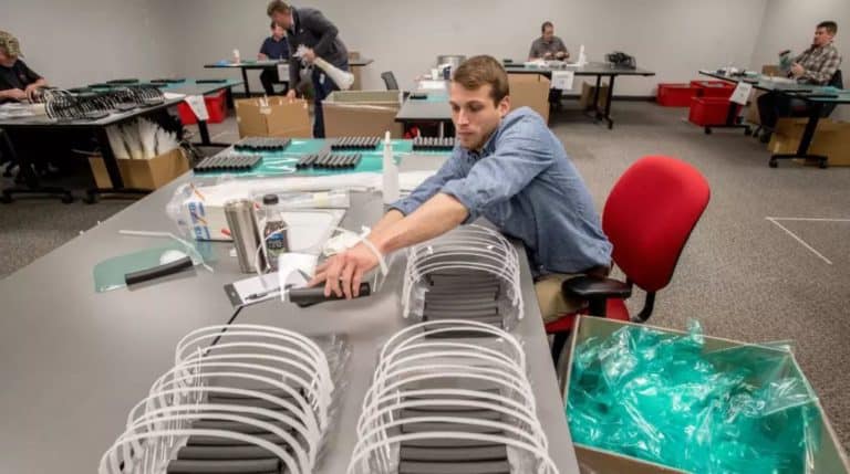 Man at table assembling face shields.