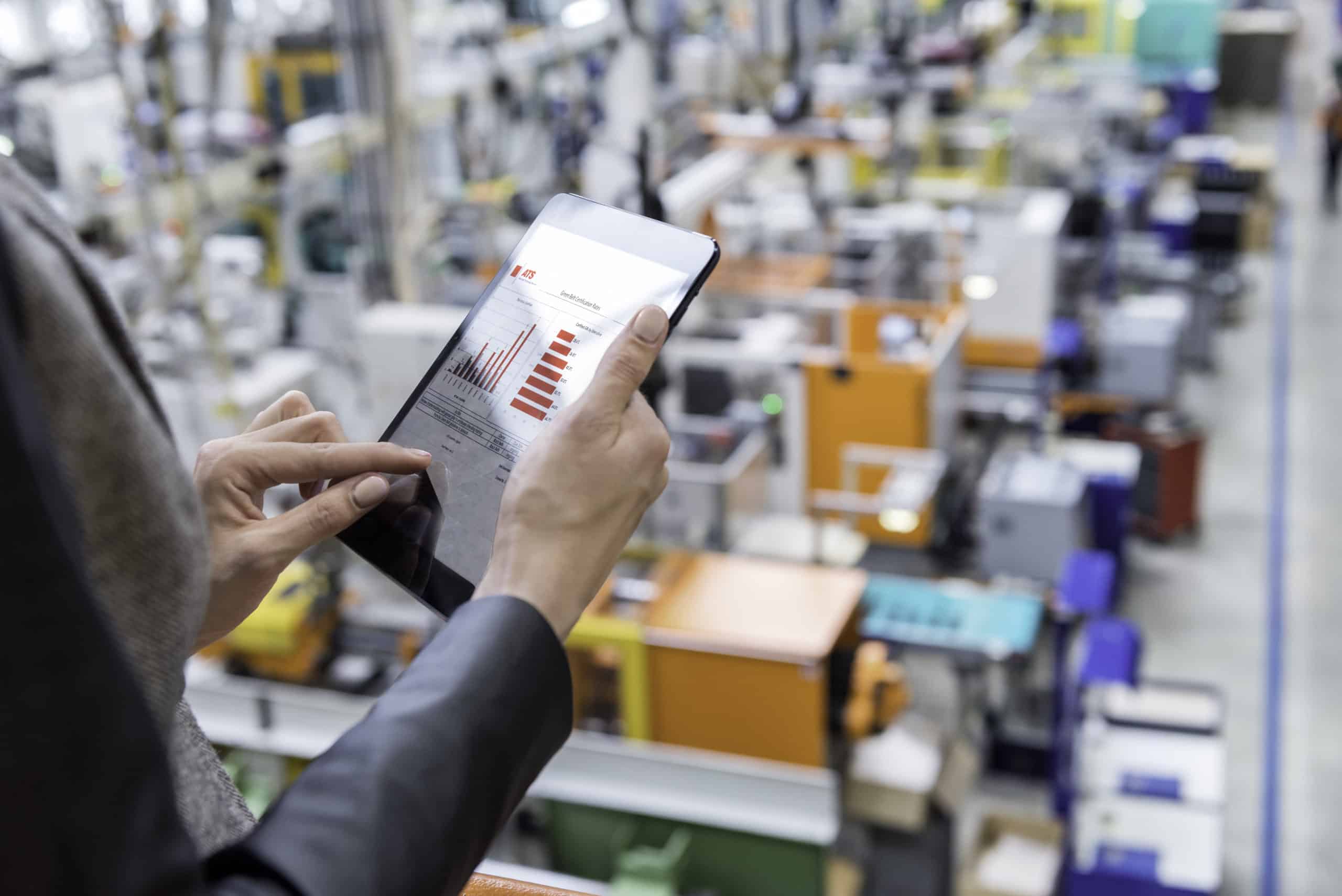 Woman overlooking factory using tablet.