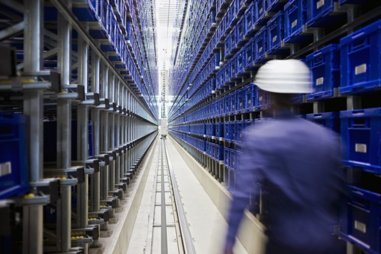 Worker walking through manufacturing storeroom.