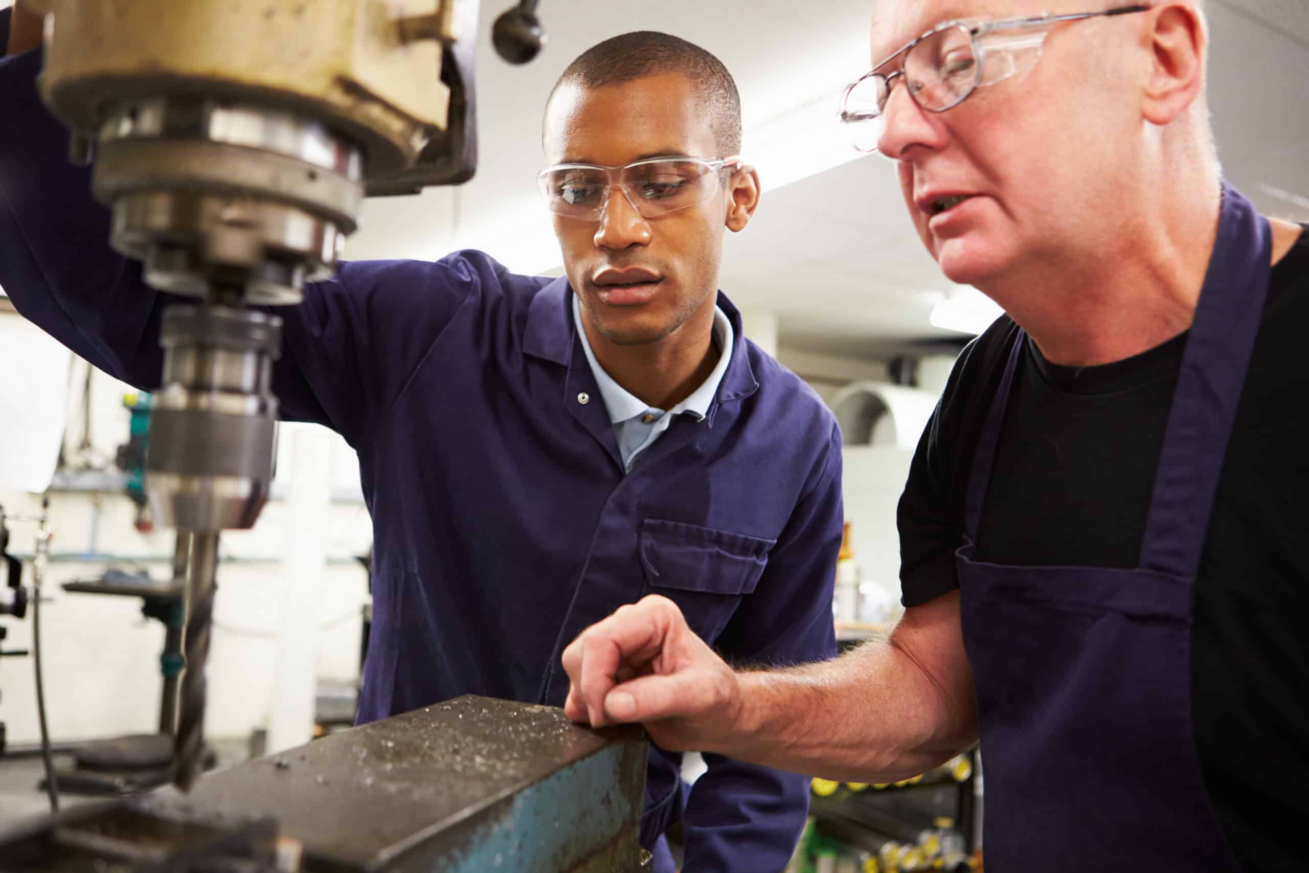 Two men in protective glasses operating machinery.