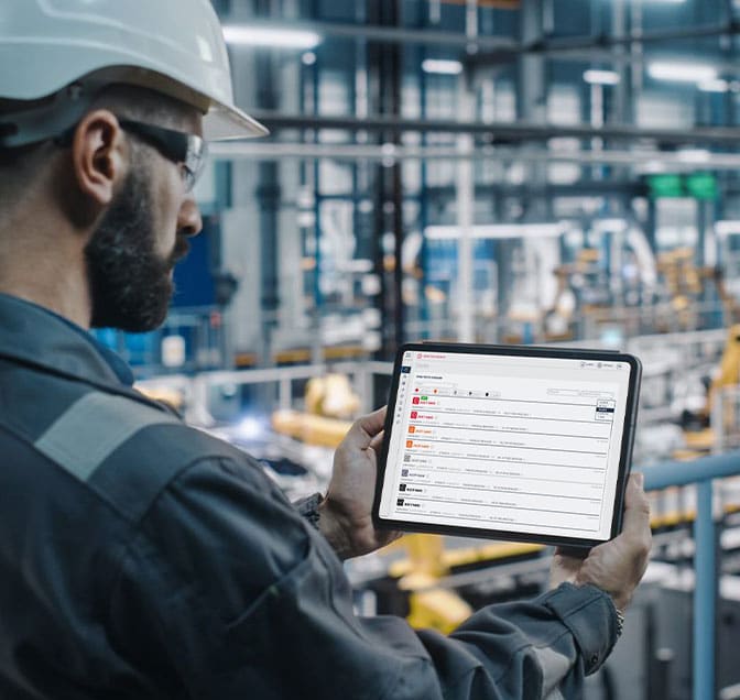 Car factory engineer in work uniform using a tablet showing machine data.