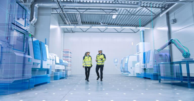 Man and woman walking in futuristic factory wearing white hard hats