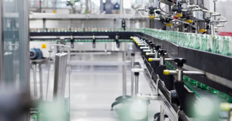 Green glass Bottles on a Conveyor in a bottling manufacturing Plant.