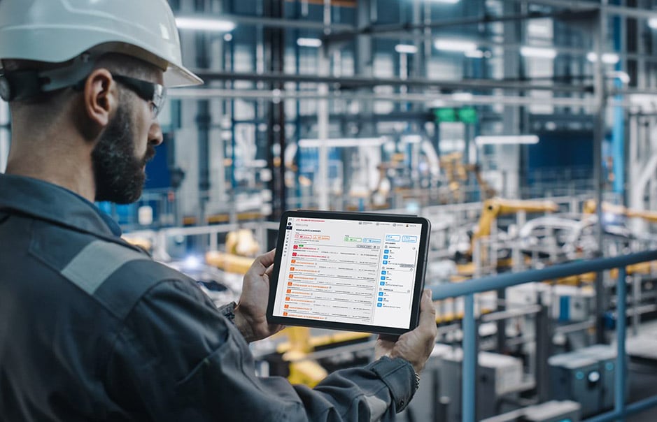 Car factory engineer in work uniform using a tablet showing machine data.