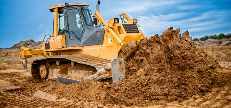 Excavator working with earth and sand in sandpit in highway construction site.