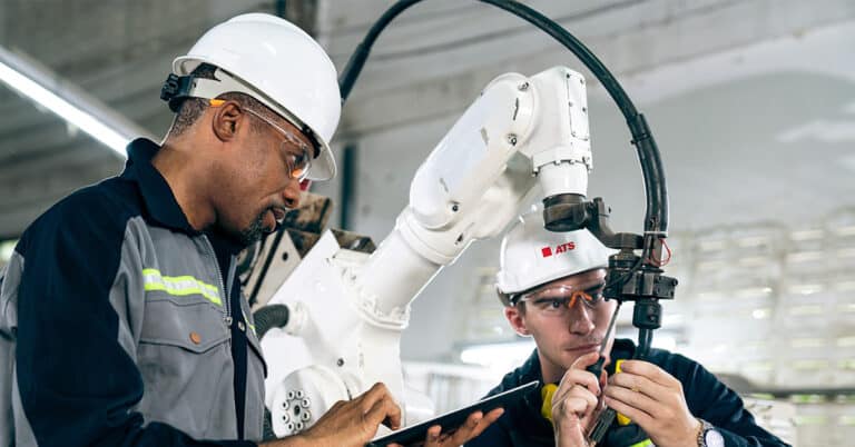 Two ATS short-term maintenance technicians working on robot maintenance in manufacturing facility.