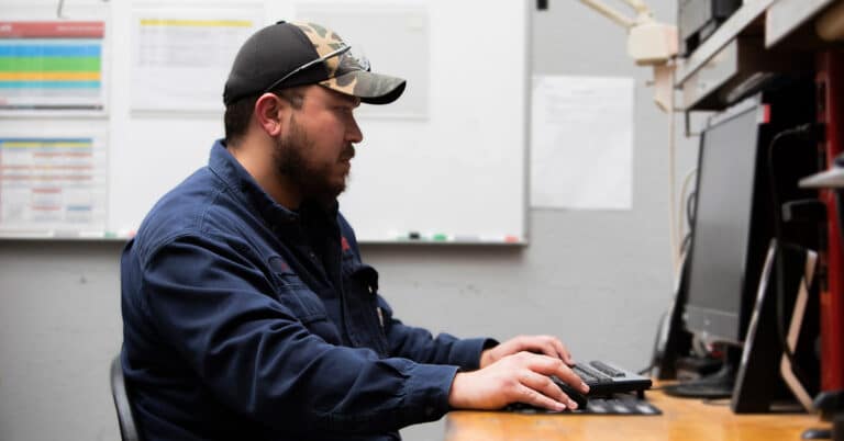 ATS technician reviewing production schedule on desktop computer.