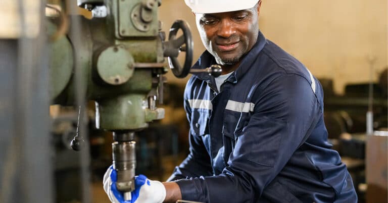Male industrial worker in white hard hat working at manufacturing plant.