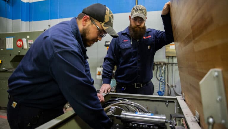 Two ATS technicians performing preventive maintenance on a piece of equipment.