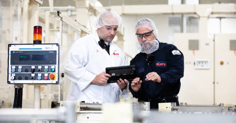 Two ATS technicians in consumer packaging goods manufacturing plant reviewing technology.