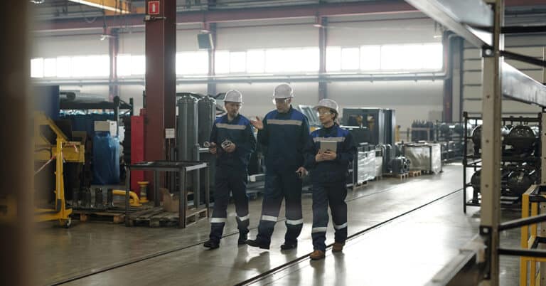 Group of three technicians walking the manufacturing plant floor.