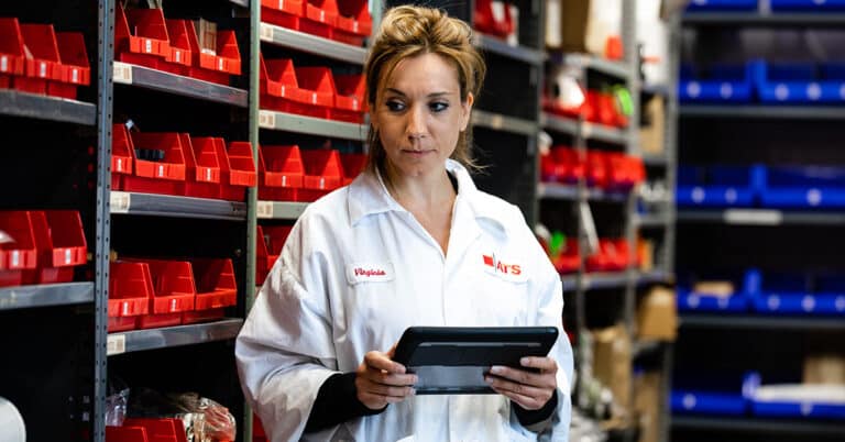 ATS female employee holding tablet computer in warehouse.