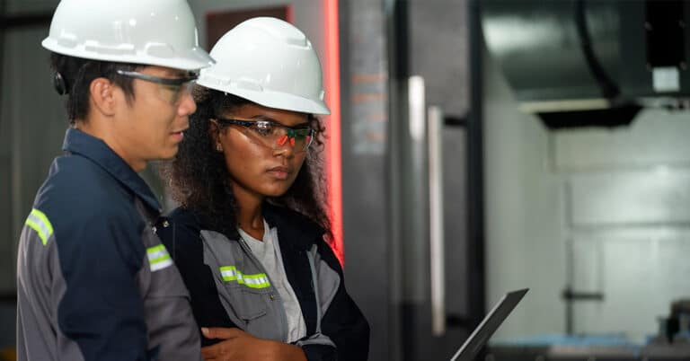 Two skilled engineers engaging in collaborative discussion while using technology.