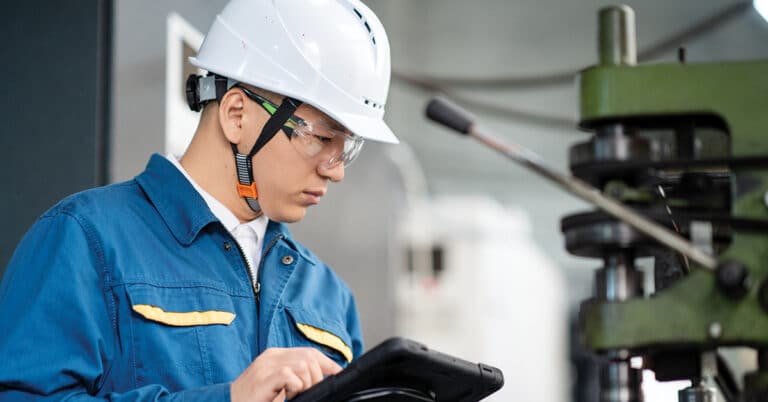 Male engineer working in factory with tablet.
