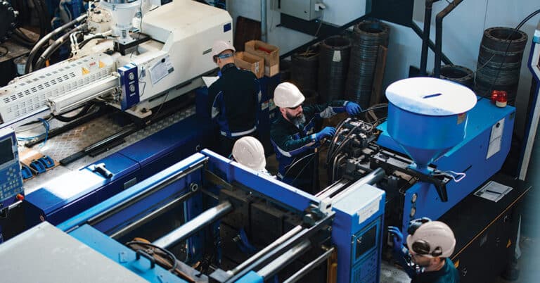 Industrial workers operating machinery in a busy factory.
