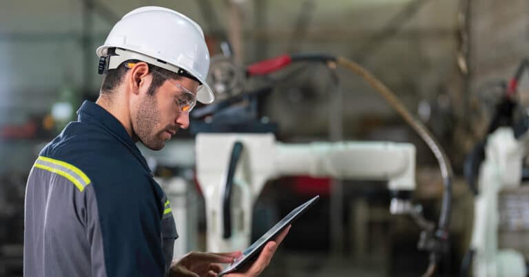 Mechanical engineer using tablet in automated manufacturing environment.