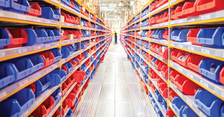 Diminishing perspective of warehouse racks filled with red and blue trays.