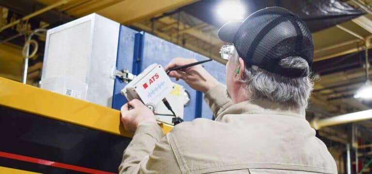 ATS technician working with sensor technology in manufacturing facility.