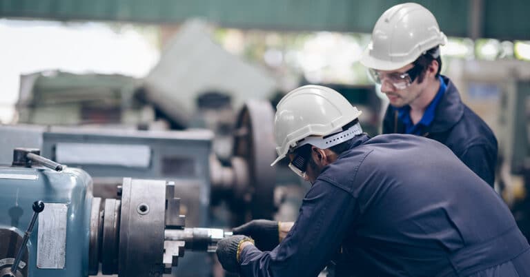 Two workers in production line as discussing at machine.