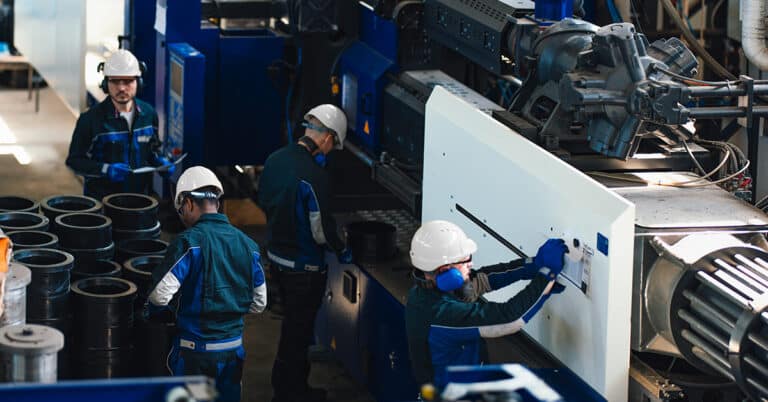 Industrial workers operating machinery in a busy factory.