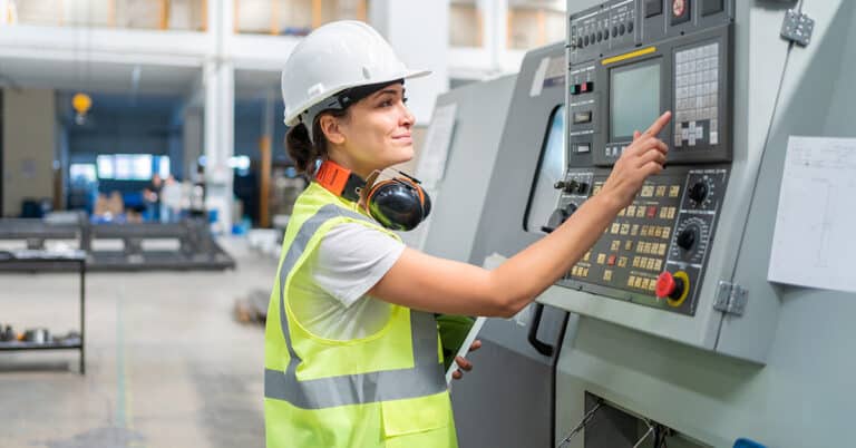 Female engineer programming a CNC machine at factory